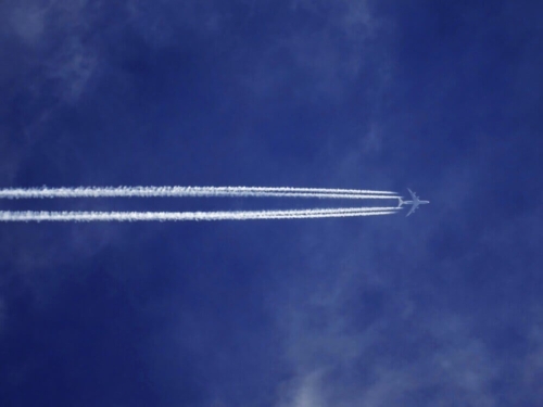 a fighter jet flying through a cloudy blue sky